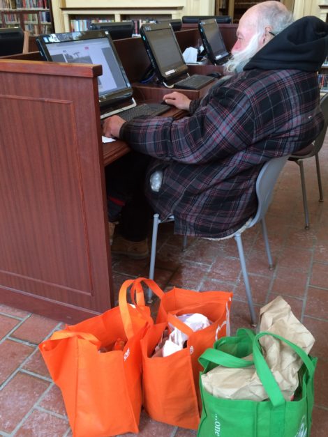 David Magadini at the Mason Library computer, accompanied by his bags of materials.