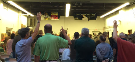 Voters standing and raising their hands during the special town meeting.