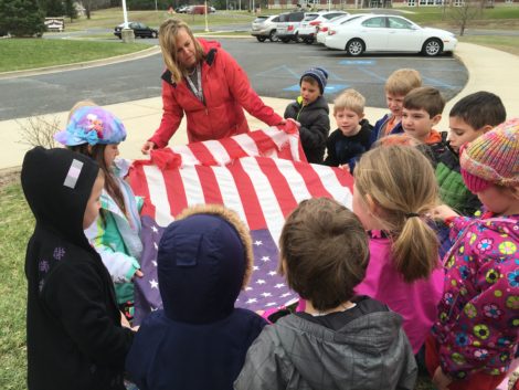 With the assistance of Amy Salinetti, her kindergarten class folds old flag that has been removed from the school's flag pole.