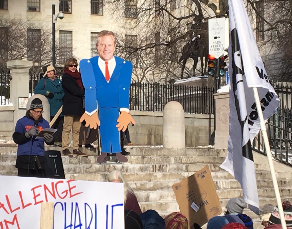 Emcee and 350 Mass volunteer Steve Miller interviews a shrugging, 9-foot-tall Charlie Baker puppet about Baker's plans for meeting Massachusetts' Global Warming Solutions Act requirements.