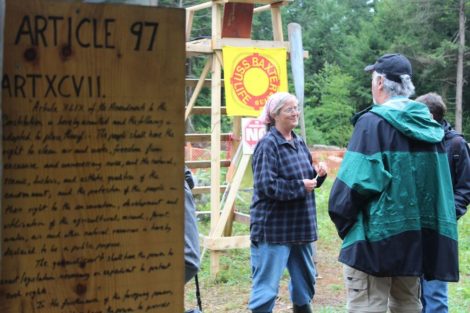 Property owner Sue Baxter talks with a protester in front of the lifeguard chair that bears her name just beyond a plaque containing the text of Article 97 of the state constitution. Photo: Terry Cowgill
