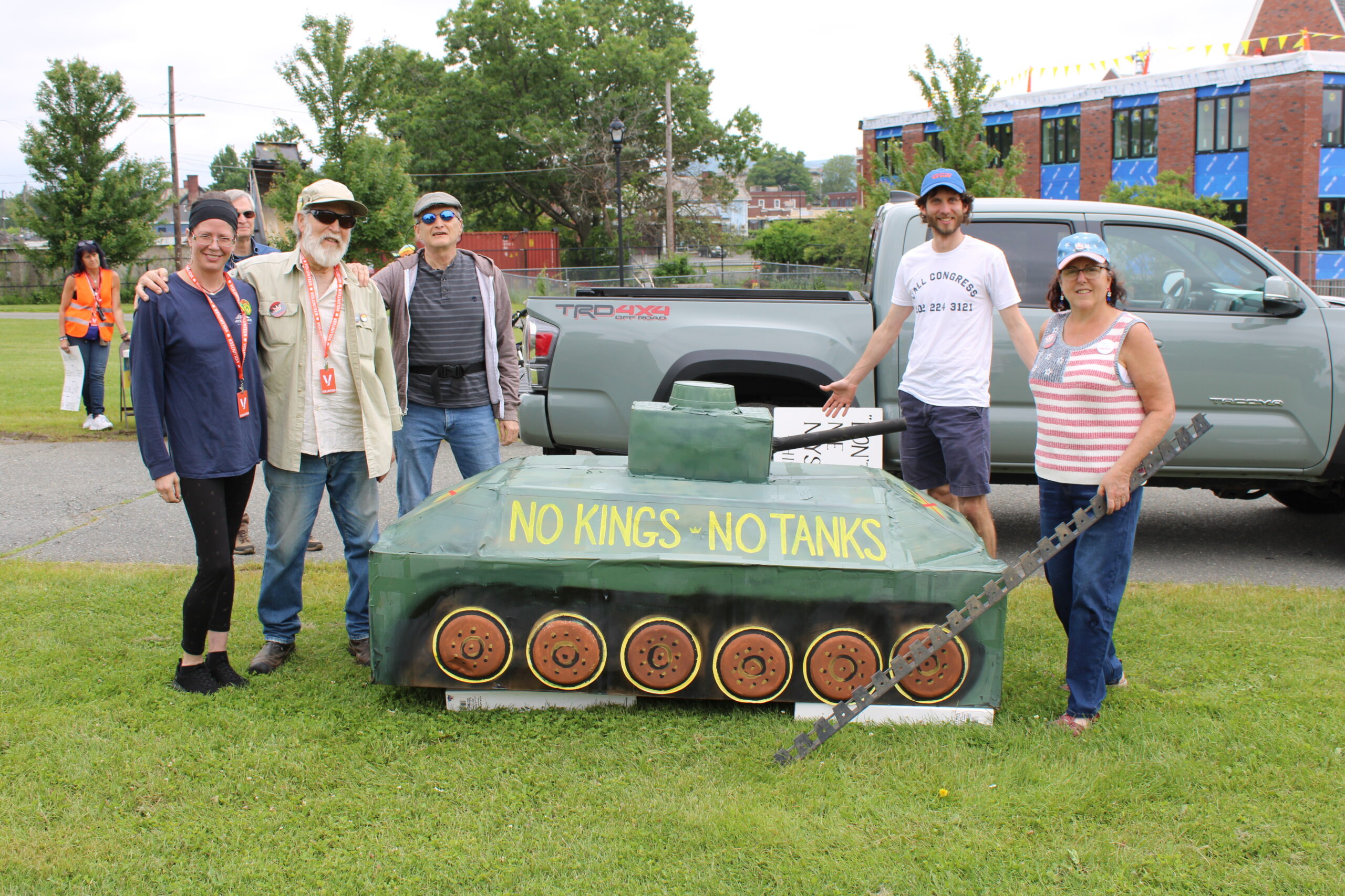 Some of the No Kings event co-organizers next to a model tank. Photo by Shaw Israel Izikson.